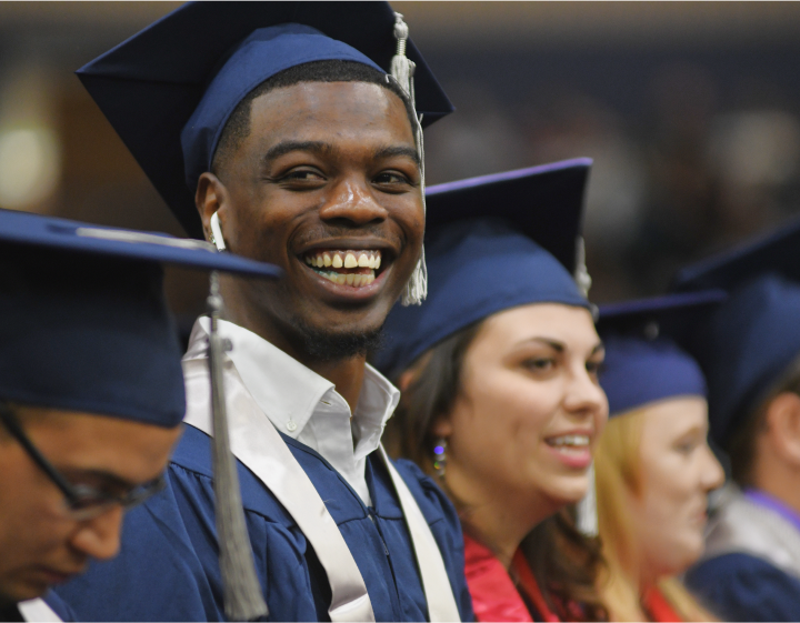 Students in graduation garb, smiling